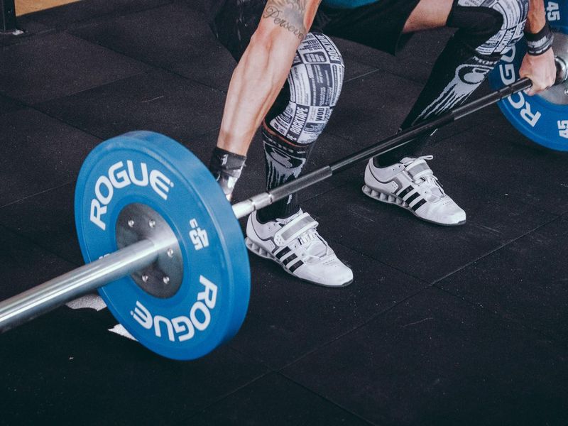 A man performing a heavy deadlift in a dark gym.